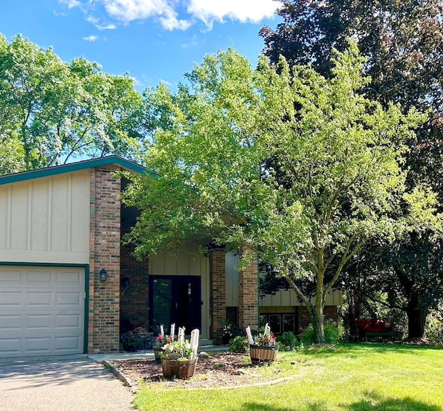 view of front of property featuring an attached garage, a front yard, board and batten siding, and brick siding