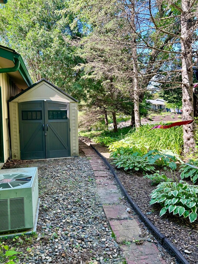 view of yard featuring a shed, cooling unit, and an outdoor structure