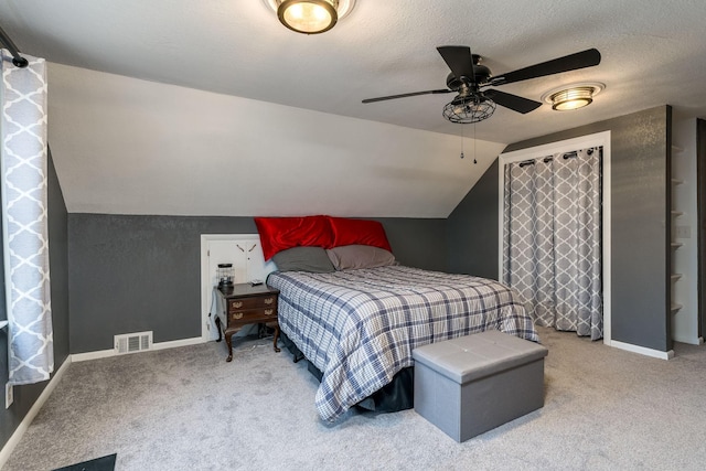 carpeted bedroom featuring ceiling fan, lofted ceiling, and a textured ceiling