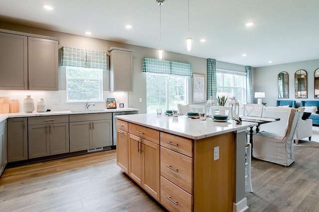 kitchen with backsplash, decorative light fixtures, light hardwood / wood-style floors, and sink