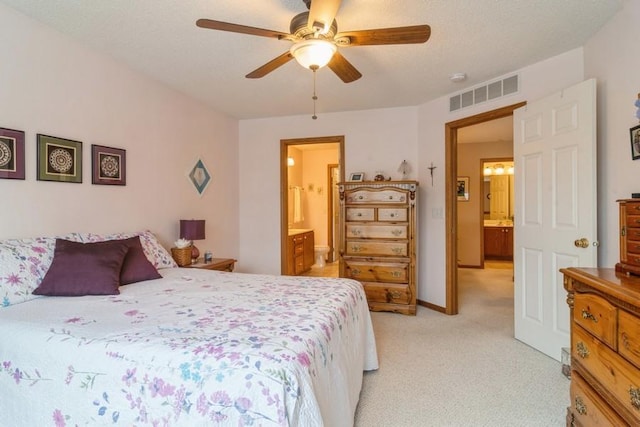 bedroom featuring ceiling fan, connected bathroom, light colored carpet, and a textured ceiling