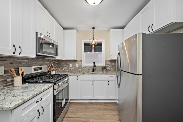 kitchen featuring white cabinets, pendant lighting, stainless steel appliances, and sink