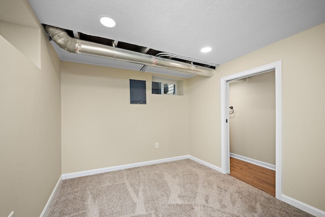 basement featuring light colored carpet and a textured ceiling