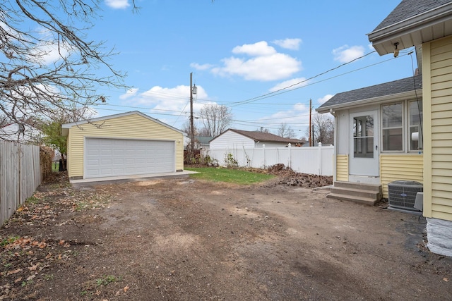 view of yard featuring a garage, an outdoor structure, and central AC