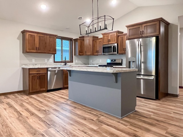 kitchen featuring a center island, hanging light fixtures, stainless steel appliances, light hardwood / wood-style floors, and a kitchen bar