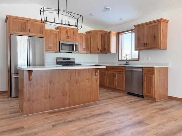 kitchen featuring a center island, decorative light fixtures, brown cabinets, stainless steel appliances, and light countertops