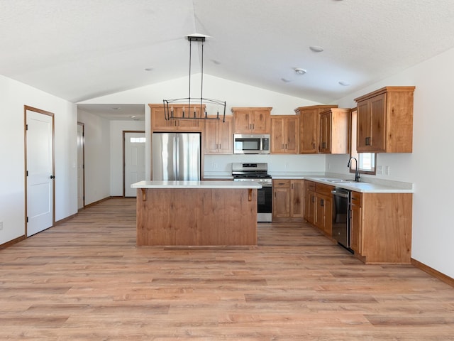 kitchen with appliances with stainless steel finishes, light countertops, a kitchen island, and hanging light fixtures