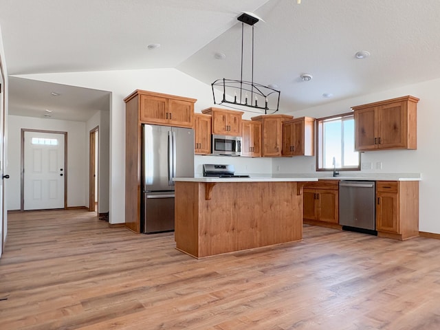 kitchen with a kitchen island, appliances with stainless steel finishes, brown cabinets, hanging light fixtures, and light countertops