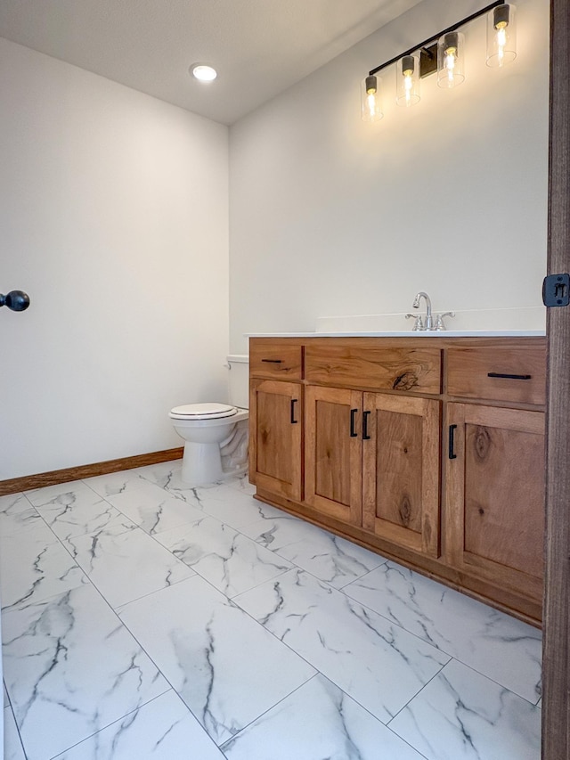 bathroom with marble finish floor, toilet, vanity, and baseboards