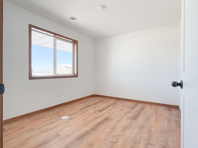 spare room featuring light wood-style floors and baseboards