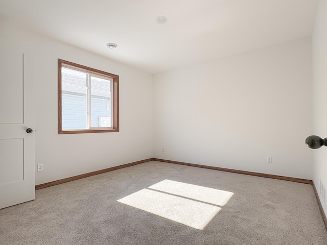 unfurnished room featuring light carpet and baseboards