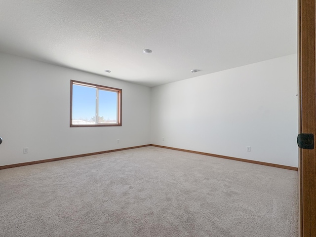 unfurnished room with light carpet, a textured ceiling, and baseboards