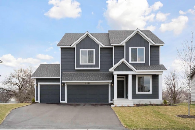 view of front facade featuring a front lawn, roof with shingles, board and batten siding, an attached garage, and driveway