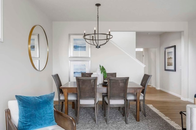 dining area featuring stairway, baseboards, wood finished floors, and a chandelier