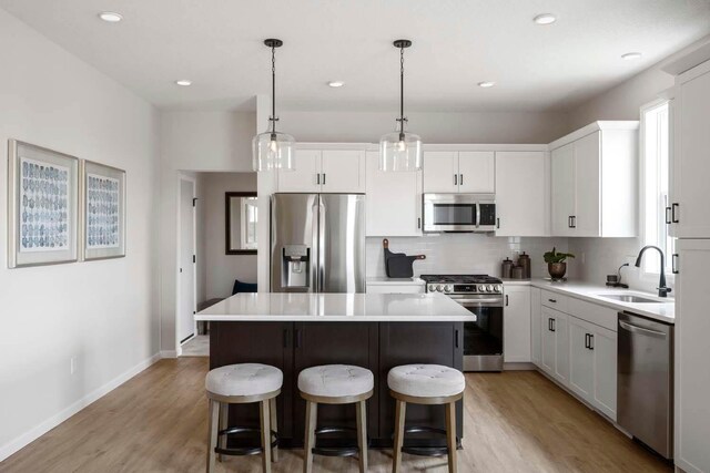 kitchen with a kitchen island, appliances with stainless steel finishes, tasteful backsplash, a sink, and light wood-style floors