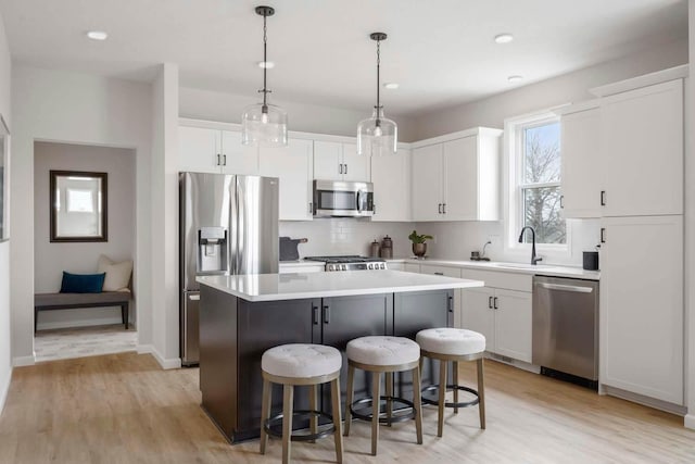 kitchen with a sink, a center island, stainless steel appliances, and light wood-style flooring