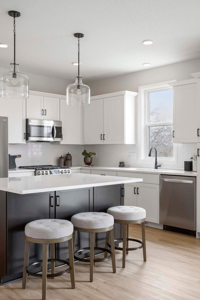 kitchen featuring light countertops, appliances with stainless steel finishes, a kitchen breakfast bar, and tasteful backsplash