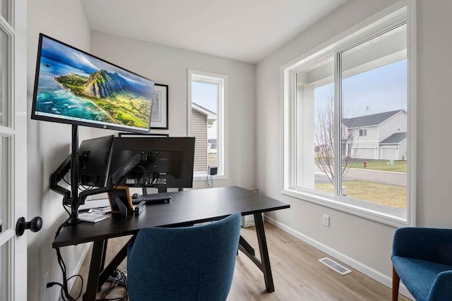 home office with baseboards, visible vents, plenty of natural light, and light wood finished floors