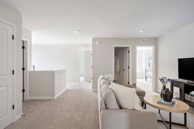 carpeted living room featuring baseboards, a textured ceiling, and visible vents