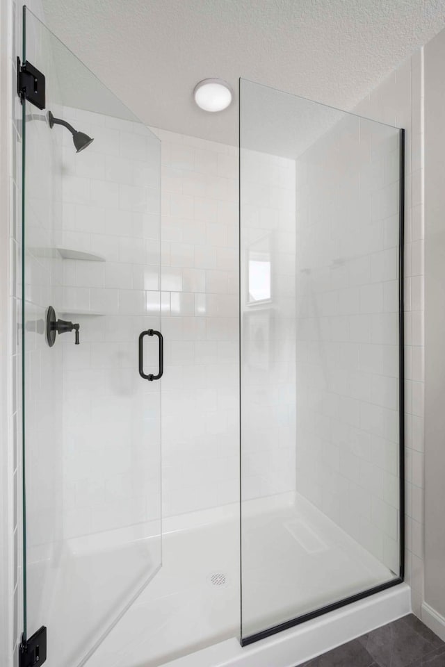 full bathroom featuring a shower stall and a textured ceiling