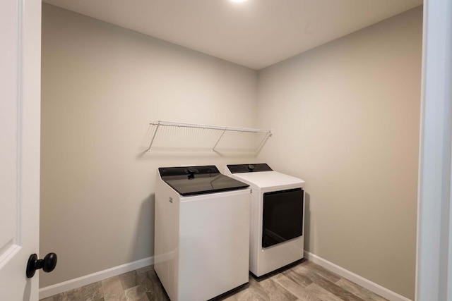 laundry area with washing machine and dryer and light hardwood / wood-style flooring