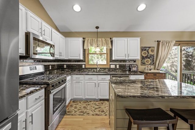 2567 Bridle Creek Trl, Chanhassen, MN 55317 - kitchen with stainless steel appliances, white cabinets, decorative backsplash, dark stone counters, and pendant lighting