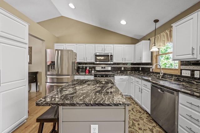 2567 Bridle Creek Trl, Chanhassen, MN 55317 - kitchen featuring appliances with stainless steel finishes, white cabinetry, vaulted ceiling, decorative backsplash, and a breakfast bar area