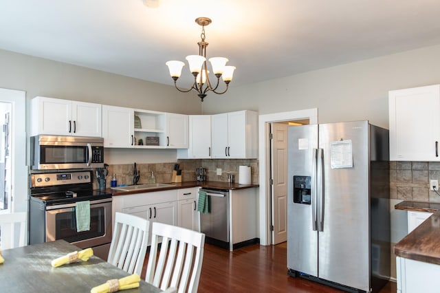 kitchen featuring appliances with stainless steel finishes, backsplash, sink, a notable chandelier, and white cabinets