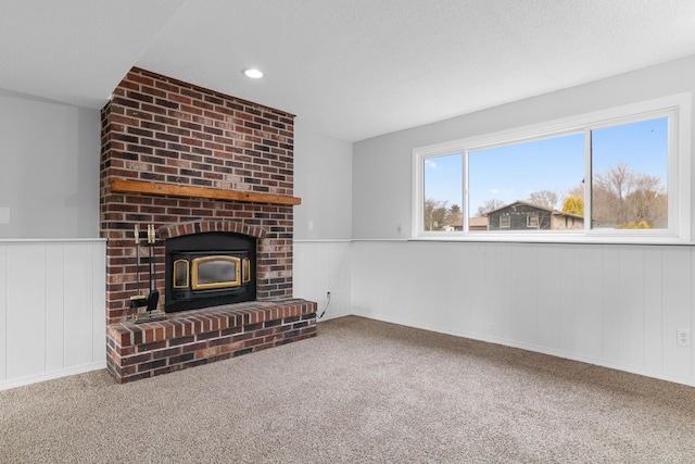 unfurnished living room with carpet flooring, a textured ceiling, and a wood stove