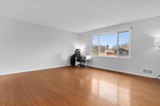 unfurnished room featuring wood-type flooring and a textured ceiling