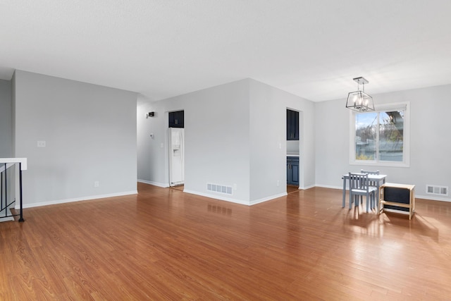 spare room with a chandelier and wood-type flooring