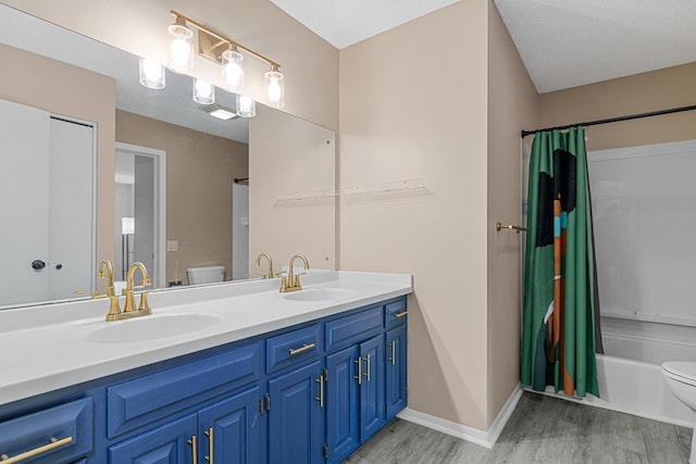 full bathroom with vanity, hardwood / wood-style flooring, toilet, a textured ceiling, and shower / tub combo