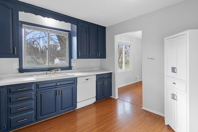 kitchen with hardwood / wood-style flooring, dishwasher, blue cabinets, and sink