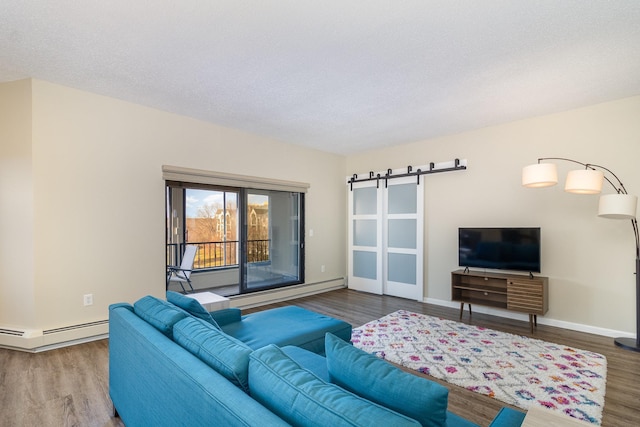 living area with a barn door, baseboard heating, wood finished floors, a textured ceiling, and a baseboard radiator