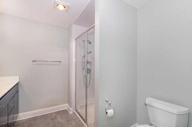 bathroom with vanity, wood finished floors, baseboards, a shower stall, and toilet