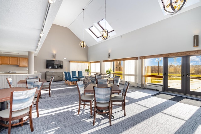 dining room featuring a skylight, track lighting, dark carpet, and high vaulted ceiling