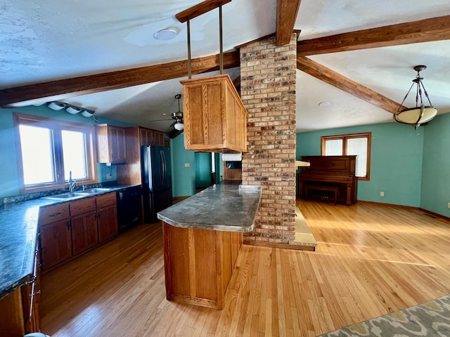 kitchen with black appliances, lofted ceiling with beams, sink, hanging light fixtures, and light hardwood / wood-style flooring