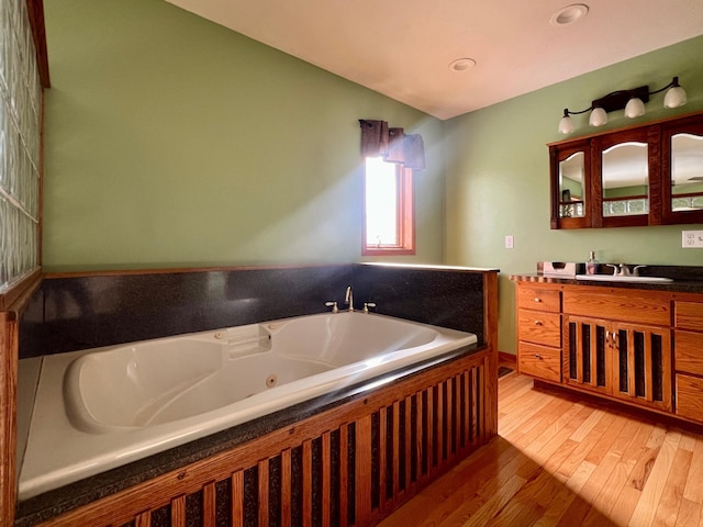 bathroom featuring hardwood / wood-style flooring, vanity, and a bath