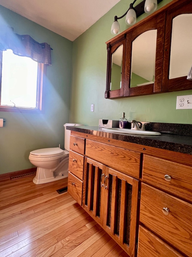 bathroom featuring vanity, hardwood / wood-style flooring, and toilet