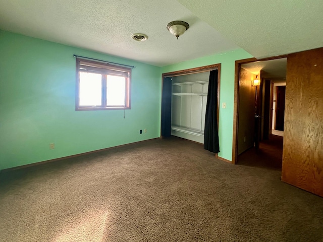 unfurnished bedroom featuring dark colored carpet, a textured ceiling, and a closet