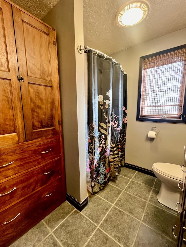 64345 370th St, Ortonville, MN 56278 - full bath with baseboards, a textured ceiling, toilet, a shower with shower curtain, and tile patterned flooring