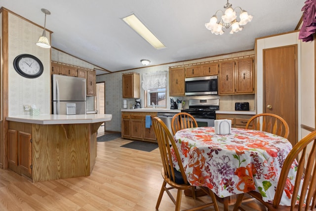 kitchen with light hardwood / wood-style floors, decorative light fixtures, vaulted ceiling, and appliances with stainless steel finishes