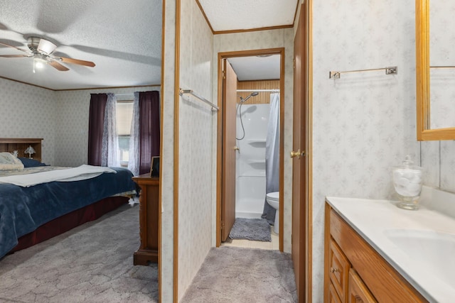 bedroom with ensuite bathroom, ornamental molding, a textured ceiling, light colored carpet, and ceiling fan