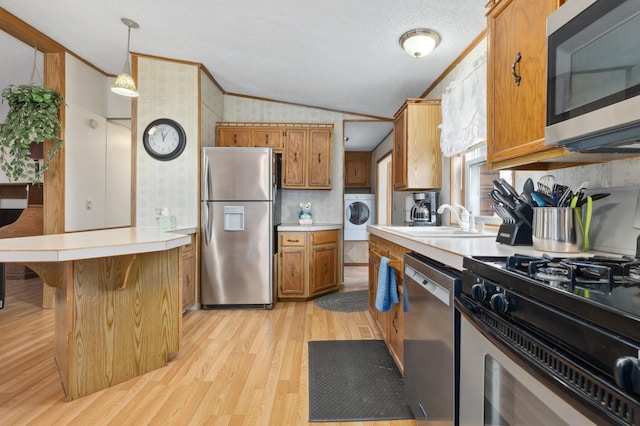 kitchen with washer / clothes dryer, light hardwood / wood-style floors, lofted ceiling, decorative light fixtures, and appliances with stainless steel finishes