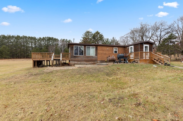 rear view of property with a wooden deck and a yard