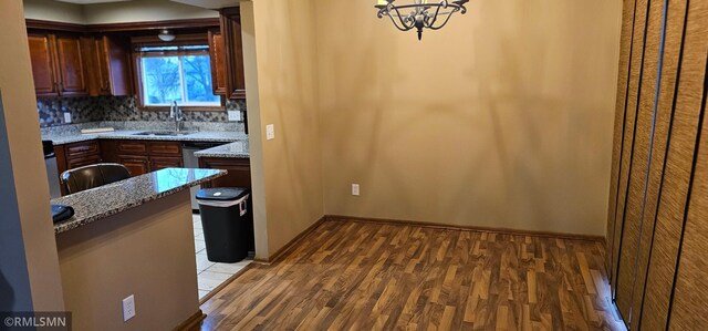 9725 Thomas Ave N, Brooklyn Park, MN 55444 - kitchen with wood finished floors, a chandelier, backsplash, and light stone countertops