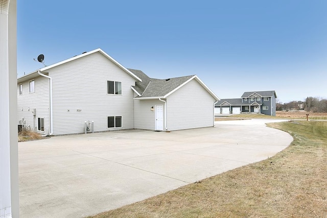 view of side of property with roof with shingles and a patio