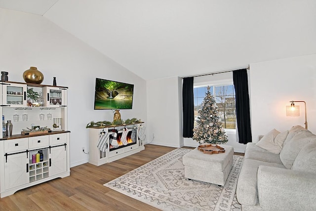 living room with lofted ceiling, light wood-type flooring, and baseboards