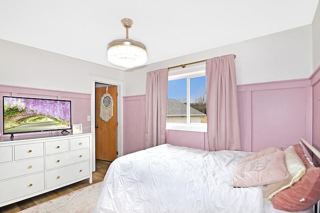 bedroom featuring a decorative wall and wainscoting