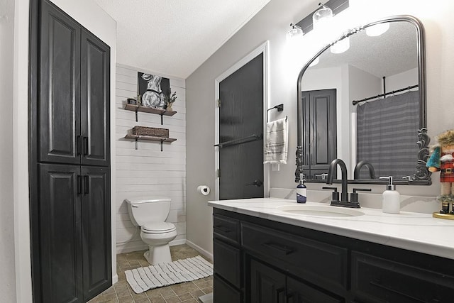 bathroom with a textured ceiling, vanity, and toilet